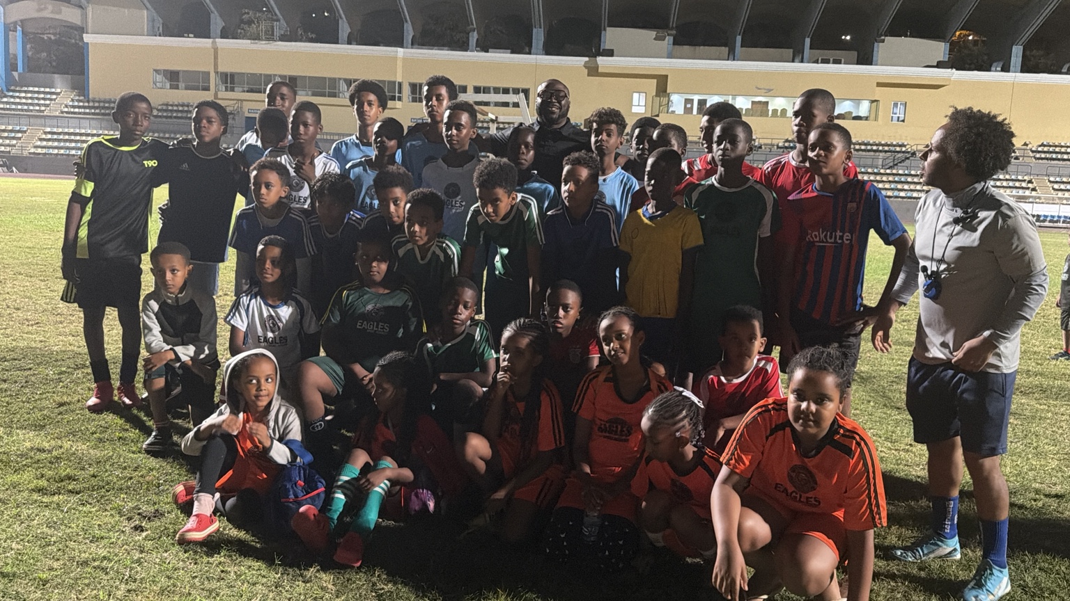 Youth football group and adults on the pitch