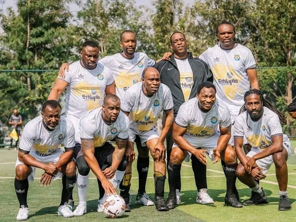 African football legends posing together on the pitch in Ethiopia